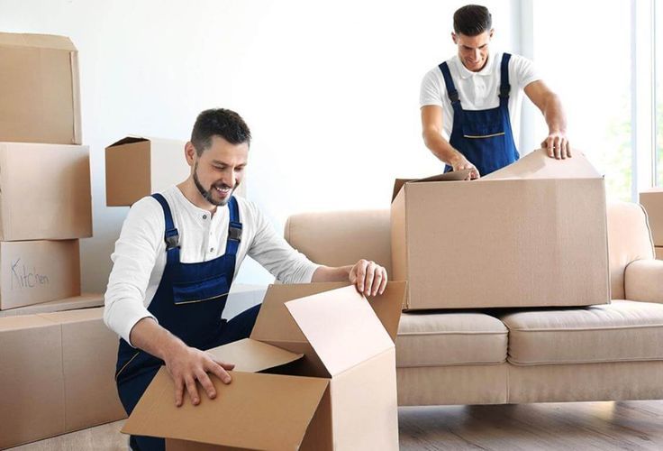 Two professional movers packing boxes in a house in Arvada, CO, carefully preparing items for a safe and efficient move.