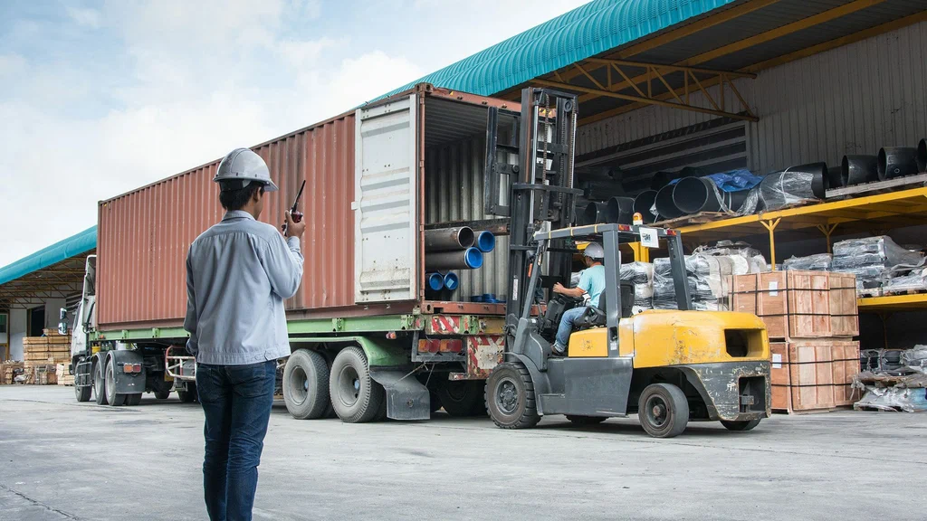 An engineer monitors the control of a container, wearing a headset with a microphone as he oversees the operation.