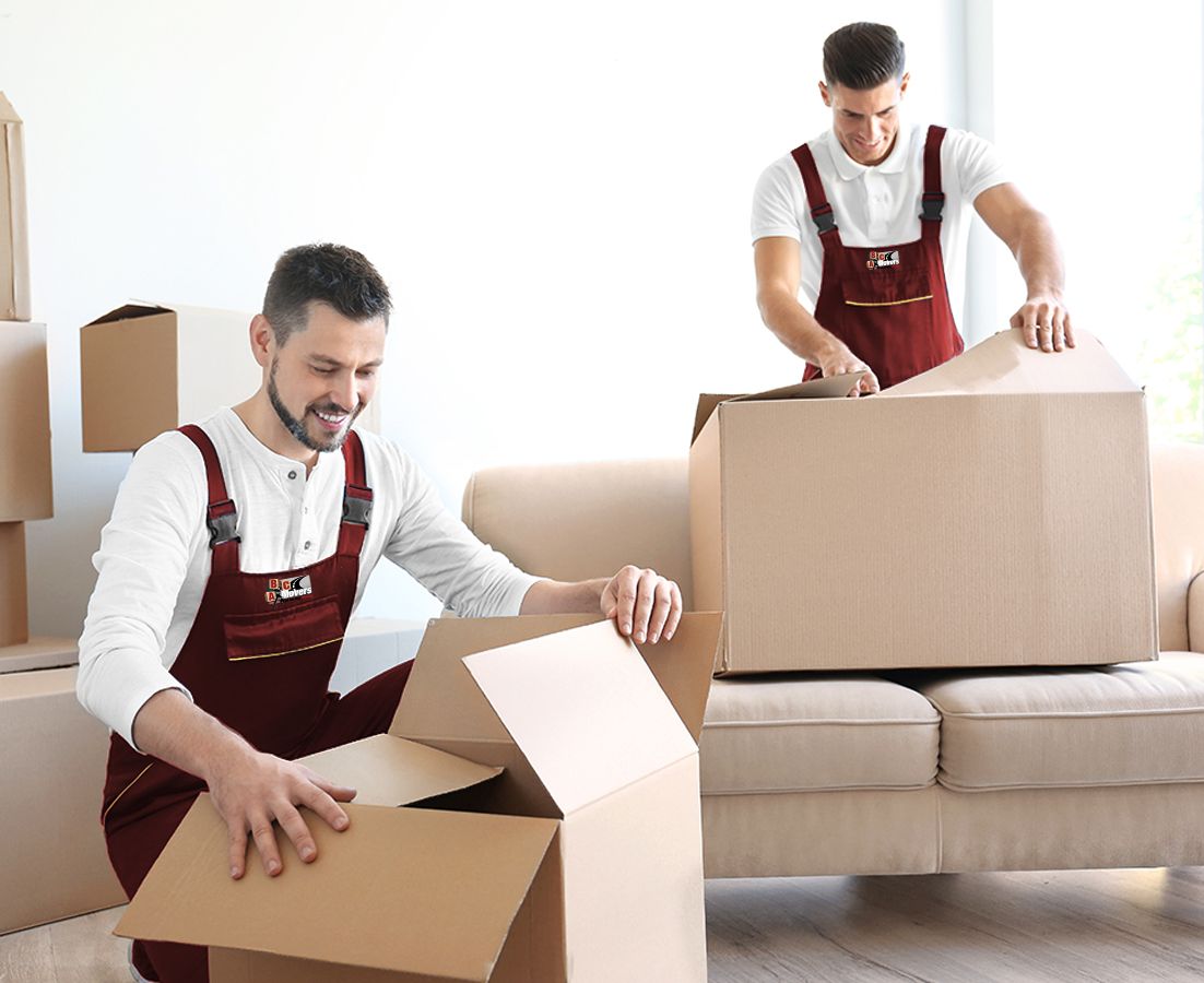 Two men pack cotton into large bales, working together to secure and organize the material for storage or shipment.