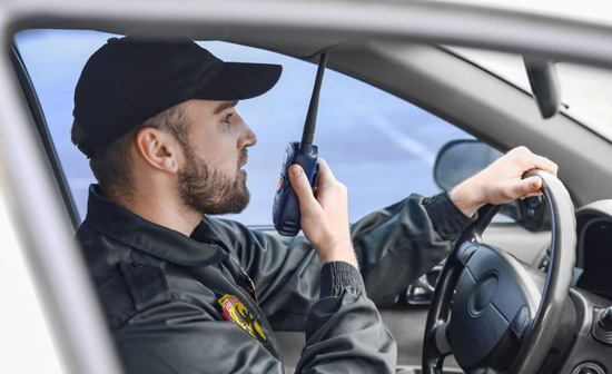 Security officer on duty inside a patrol car using wireless communication.