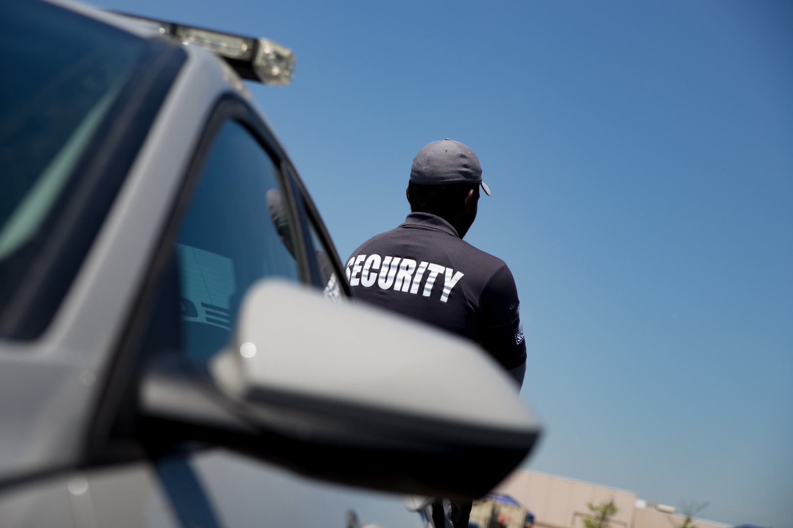 Security guard standing near a patrol vehicle, monitoring surroundings